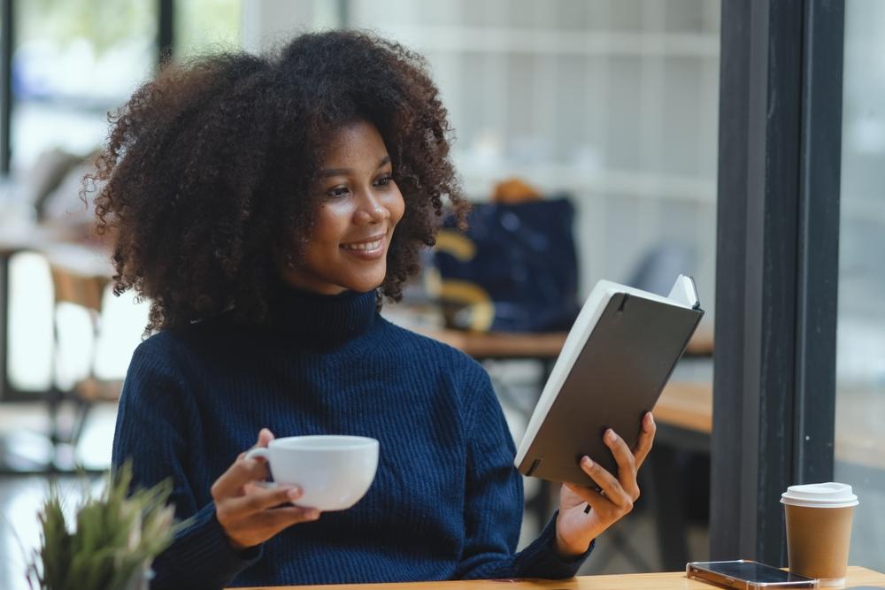 Young,African,American,Woman,Reading,A,Book,And,Sitting,At